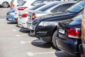 This is a photograph of cars parked in a lot on a hot day.